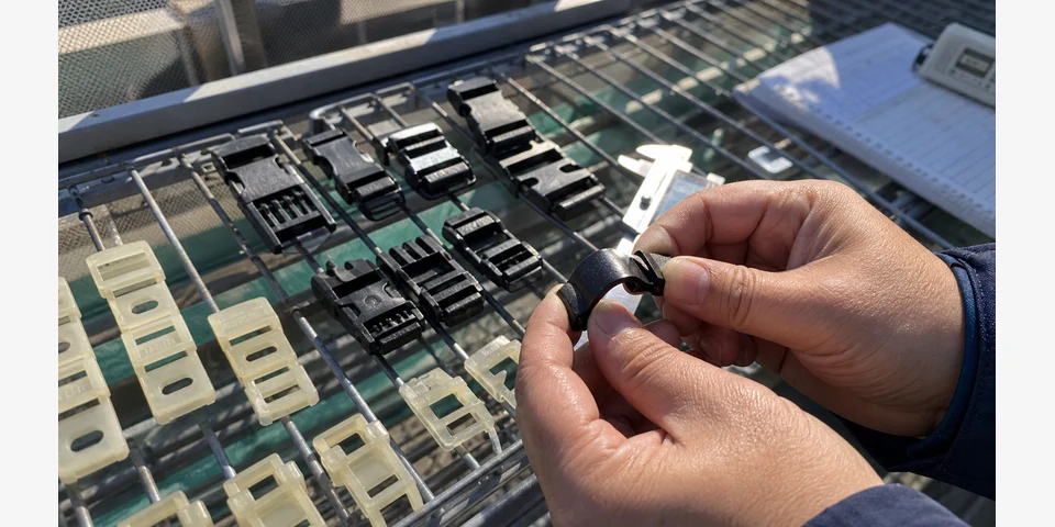 Close-up field inspection of UV-resistant PP fastening clips mounted on outdoor equipment after weathering exposure